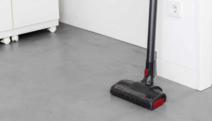 Modern Cordless vacuum cleaner leaning on a wall of a room. Home