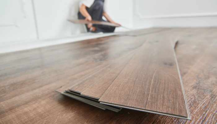 worker laying vinyl floor covering at home renovation