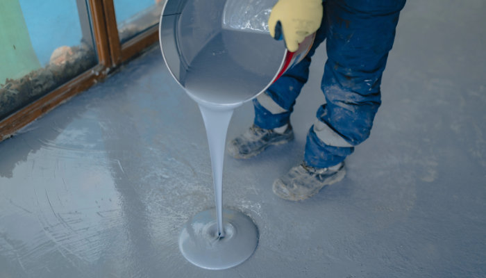 The worker applies gray epoxy resin to the new floor