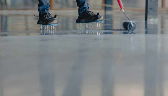 The worker applies gray epoxy resin to the new floor
