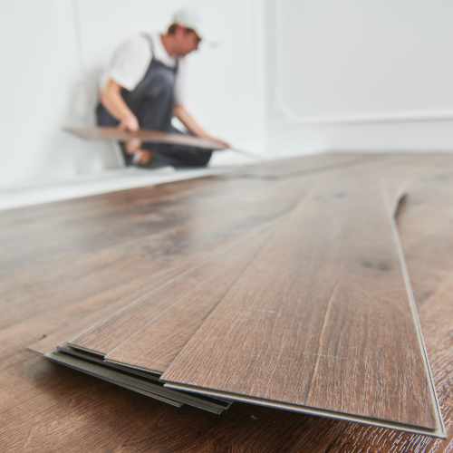 worker laying vinyl floor covering at home renovation